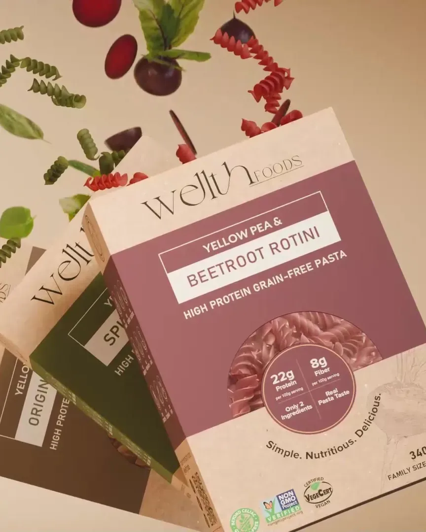 Wellth Foods pasta boxes with rotini and spinach in the air